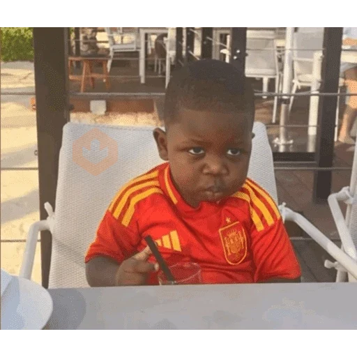 Niño pequeño con gafas de sol, sentado en una silla alta y vestido con una camiseta roja del FC Barcelona. Mira hacia un lado con expresión seria.