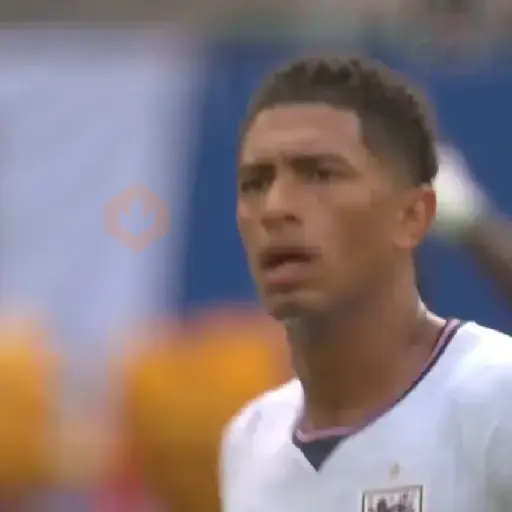 Jude Bellingham con camiseta blanca de Inglaterra, mirando hacia arriba con expresión de preocupación o duda. Fondo borroso de estadio.