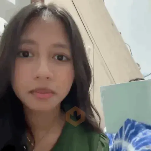 Selfie de una chica joven con cabello oscuro largo, expresión seria y mirada fija a la cámara, fondo interior con tonos verdes y azules
